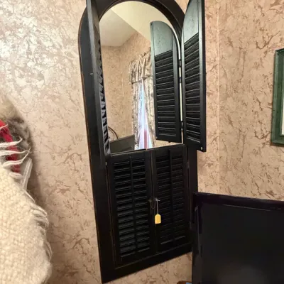 Sale Photo Thumbnail #275: Tall wall mirror featuring a wooden arched frame with opening shutter doors on the top and bottom.