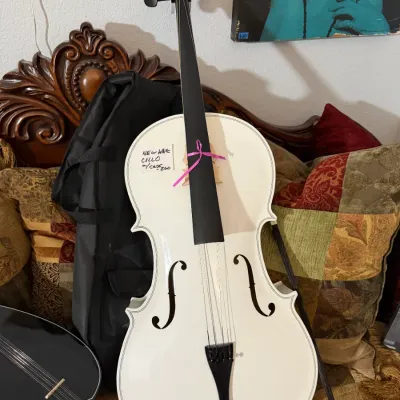 Sale Photo Thumbnail #115: Modern white full-size cello with black fingerboard, tailpiece, and tuning pegs, presented with a black padded gig bag.