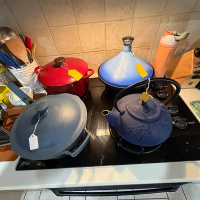 Sale Photo Thumbnail #257: Collection of colorful cast iron cookware including a red Dutch oven, a blue tagine, a matte blue pan with lid, and a textured blue teapot.