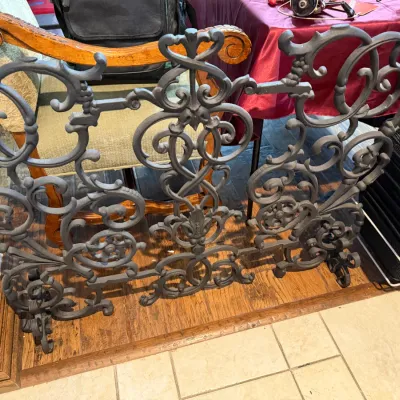 Sale Photo Thumbnail #161: Ornate wrought iron fireplace screen featuring intricate scrollwork and floral details, painted in a dark matte finish. (2 available)