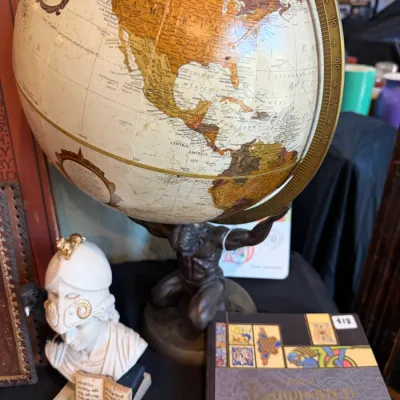 Sale Photo Thumbnail #86: Vintage Replogle world globe featuring a Atlas statue base, displayed alongside a classical bust figurine and decorative books.