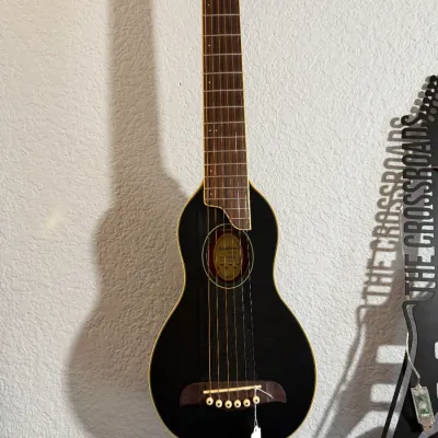 Sale Photo Thumbnail #91: Washburn Rover travel acoustic guitar in black with cream binding, featuring a compact paddle-style body and full-scale neck.