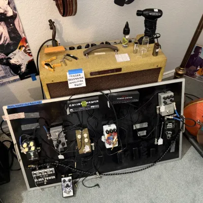 Sale Photo Thumbnail #112: Fender tweed Bassman amplifier alongside a fully loaded guitar pedalboard with power supplies and various effect pedals.