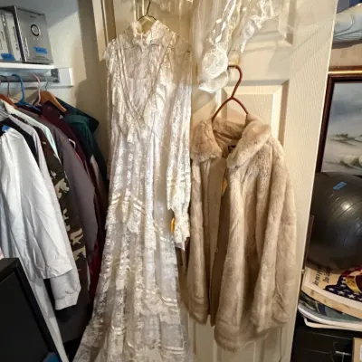 Sale Photo Thumbnail #269: Vintage high-neck lace wedding dress with ruffled details and matching veil, displayed alongside a mid-century faux fur coat.