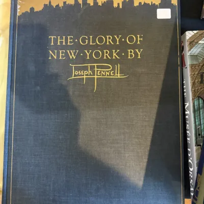 Sale Photo Thumbnail #83: Vintage hardcover copy of "The Glory of New York" by Joseph Pennell, featuring a dark cloth binding with gold foil lettering and a cityscape skyline illustration.