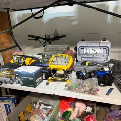 Sale Photo Thumbnail #346: Collection of tools, workshop hardware, safety gear, and craft supplies, including a yellow work light, Dremel rotary tool set, and boxed respirator mask.