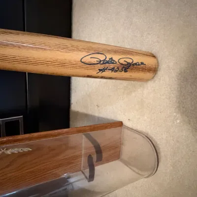 Sale Photo Thumbnail #42: Pete Rose autographed wooden baseball bat with "#4256" inscription, shown next to a clear acrylic and wood display case.