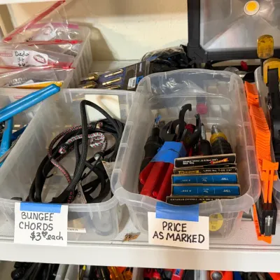 Sale Photo Thumbnail #315: Assorted workshop tools and hardware organized in clear plastic bins, including bungee cords, pliers, staple boxes, and hand tools.